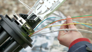 Technicians installing optic fiber with cable ties.