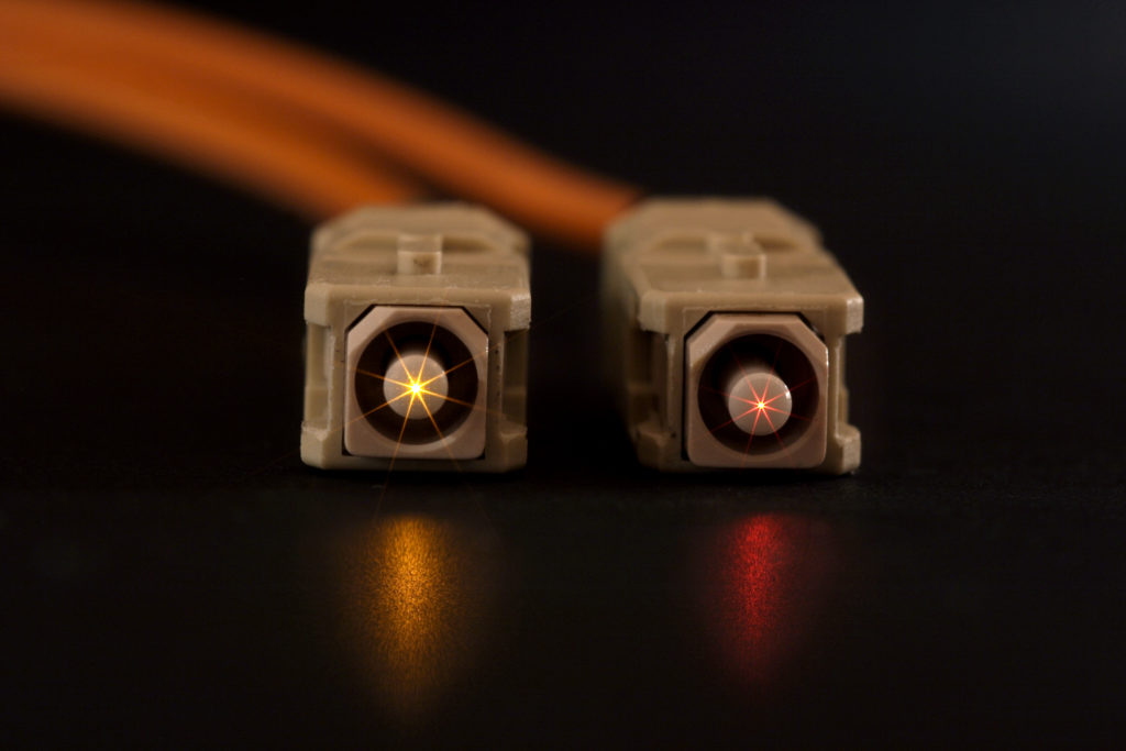 Glowing fiber cable ends with SC connectors isolated on a black background.